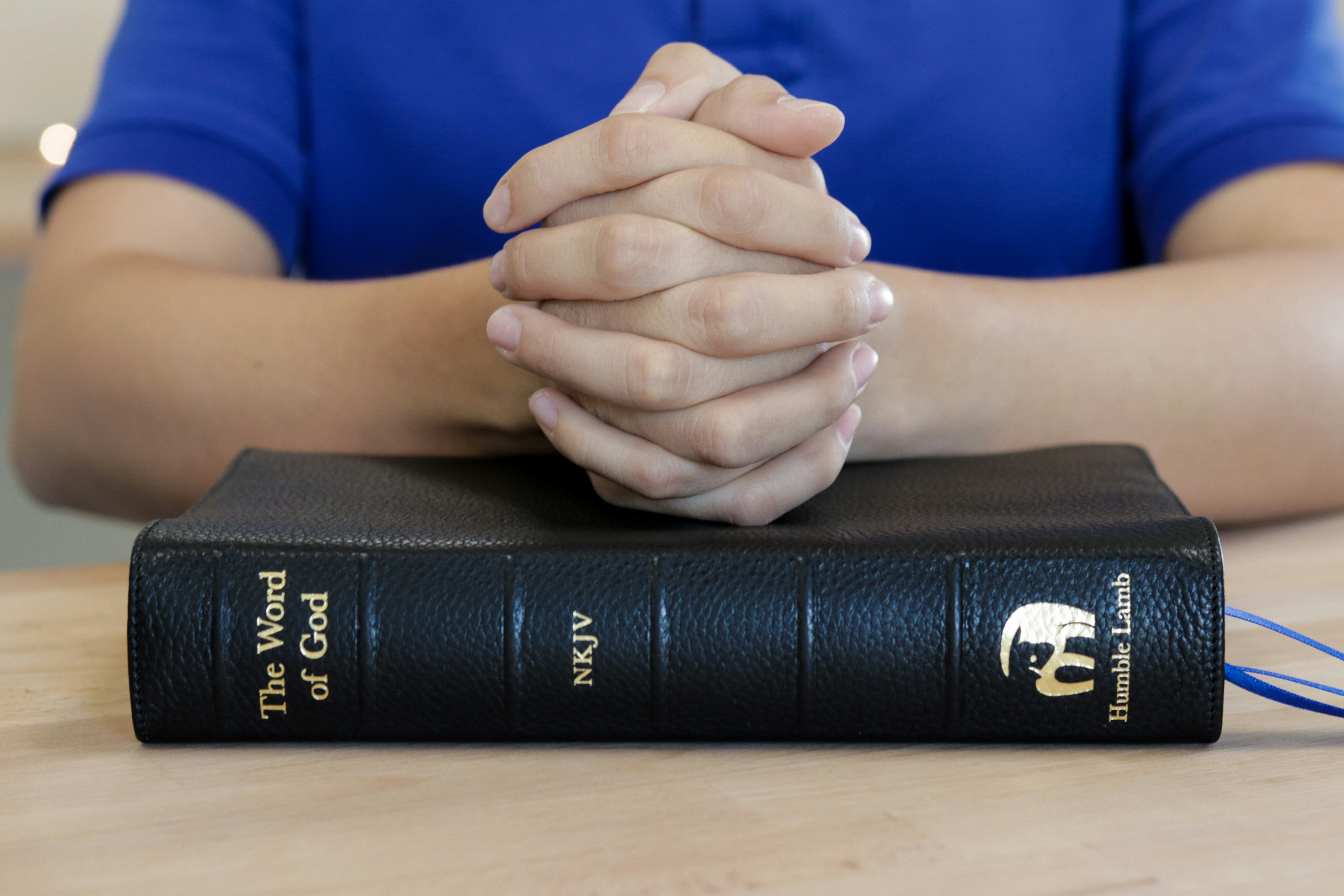 Mains en prière sur une Bible - représentant la foi et la spiritualité
